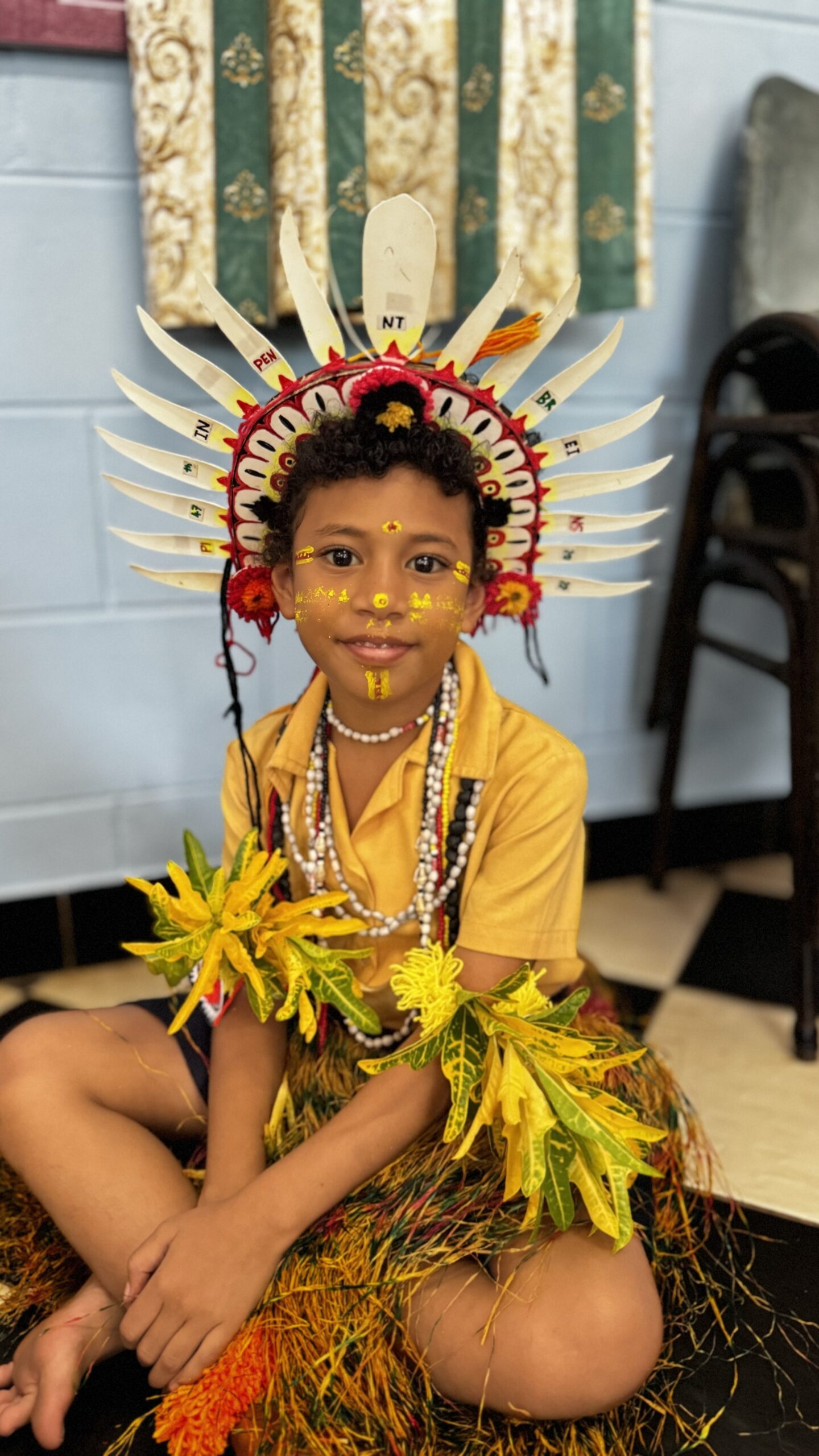 Niño con traje tradicional de Papúa Nueva Guinea, con tocado de plumas y pintura facial dorada