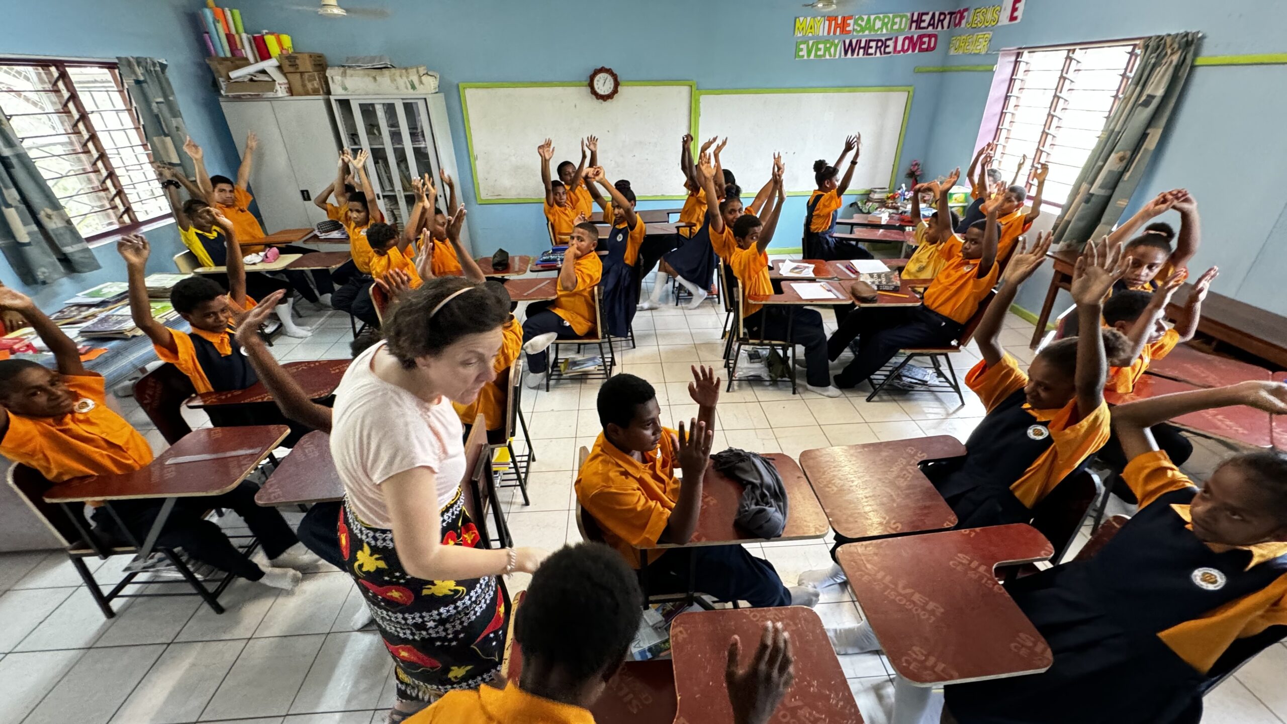 Aula cooperativa en Papúa Nueva Guinea: todos los alumnos con la mano levantada durante una sesión de coaching